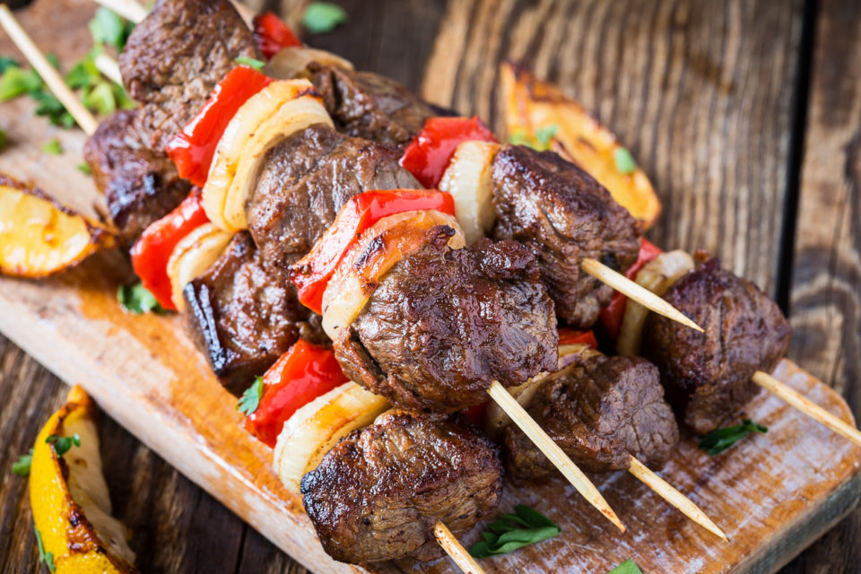 summertime means kabobs. A pile of grilled kabobs on a wooden tray.